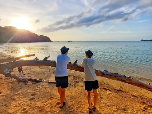 夕日輝くビーチを歩くカップル